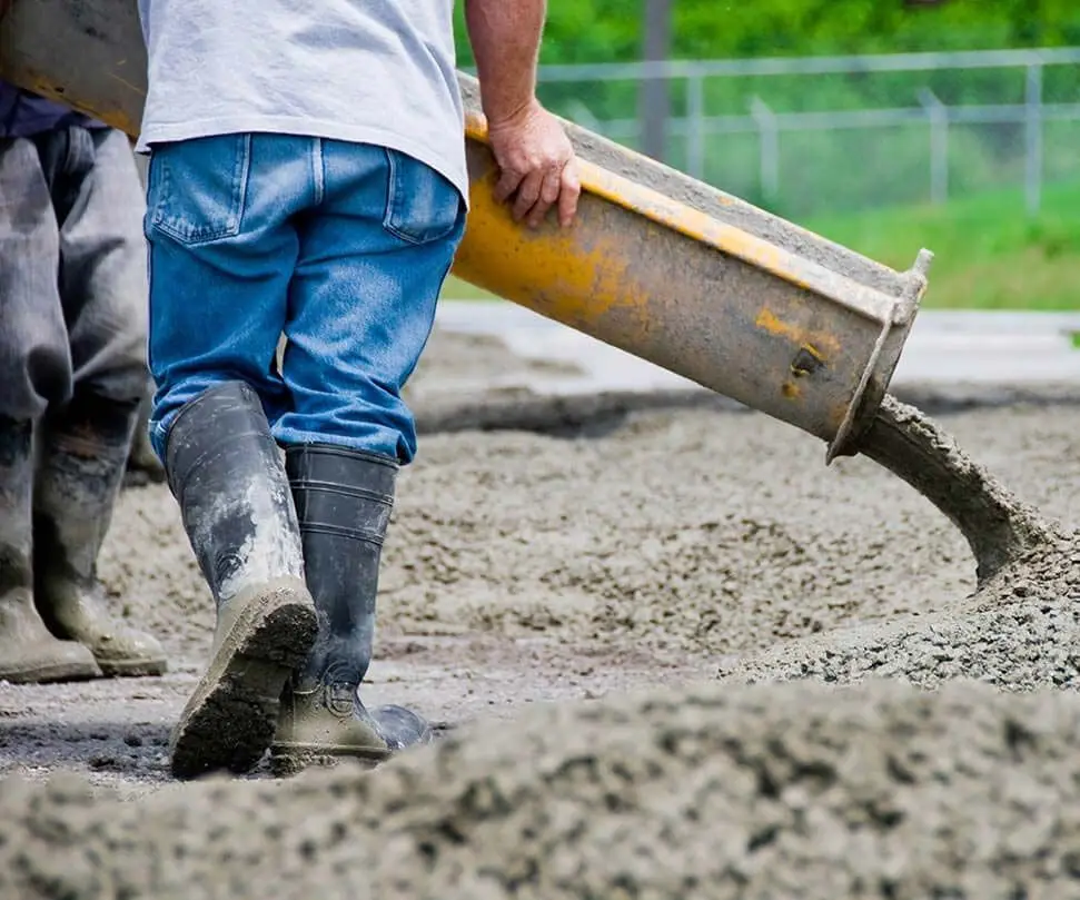 Workers pouring concrete from a chute onto a new slab